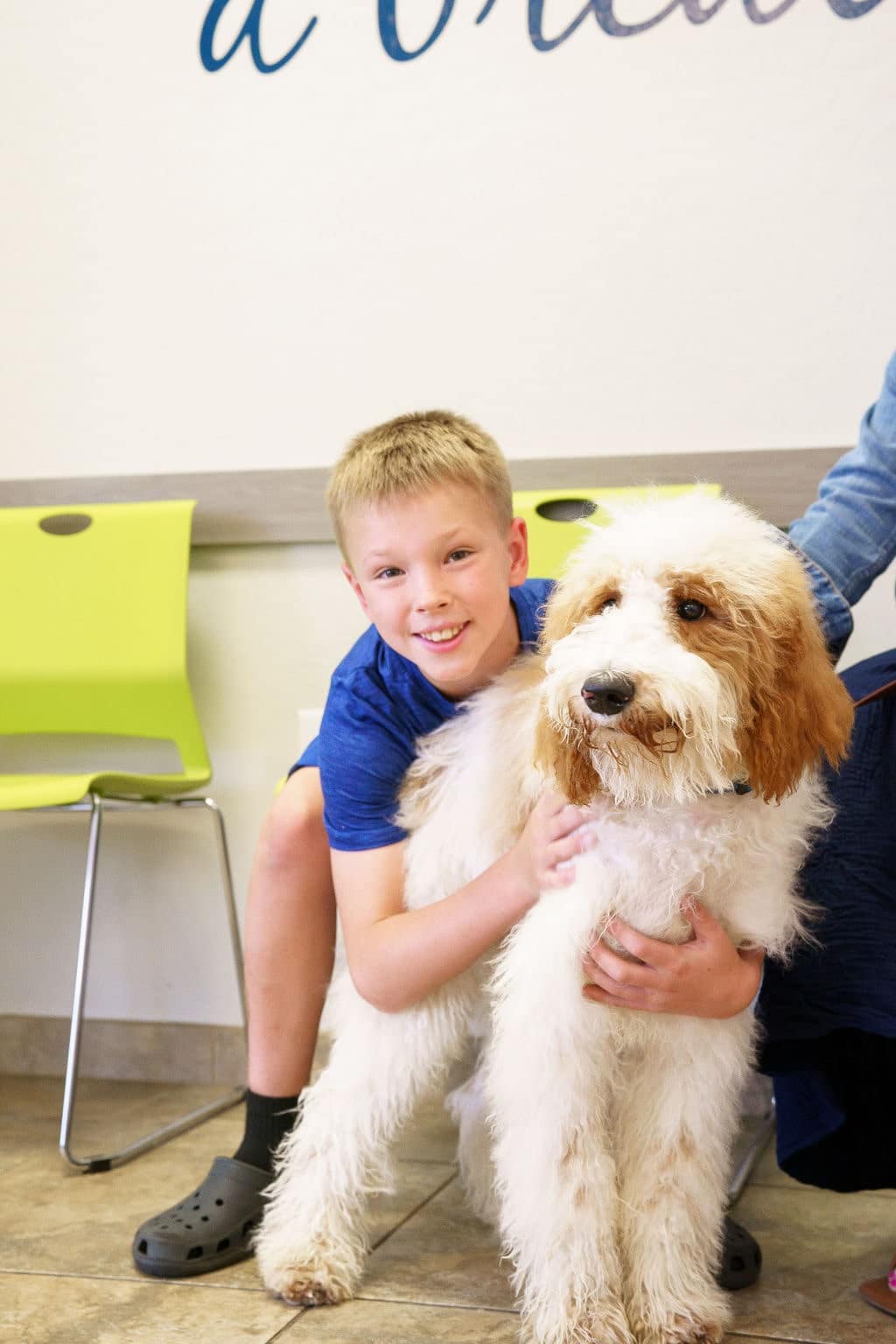 A boy smiles while hugging his dog in the waiting room at Dr. Kelly’s Surgical Unit.